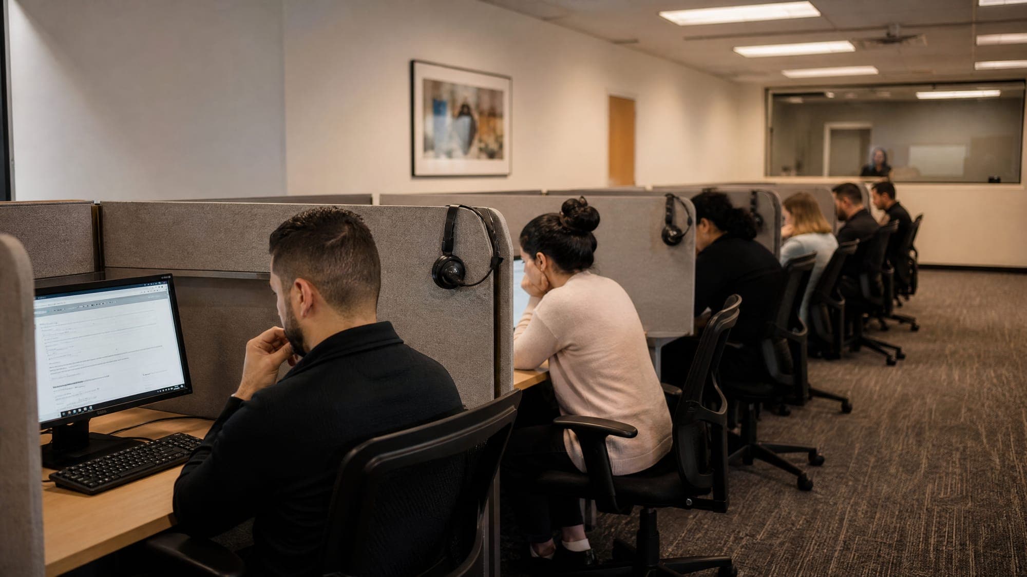 The testing room — candidates at partitioned workstations with headphones available